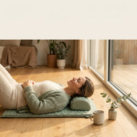 Woman relaxing on the acupressure mat by a window