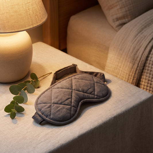 Contoured weighted sleep mask on a nightstand