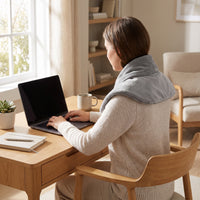 Person working at a desk wearing the cordless heated neck wrap