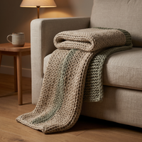 Chunky oat and sage knit weighted blanket folded over the arm of a linen sofa