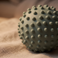 Close-up of the sage reset ball's nubbed surface in warm lamplight