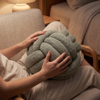 Hands resting on the sage weighted knot pillow held in a lap