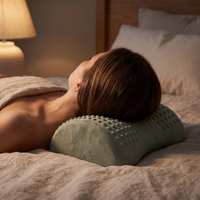 Woman resting the back of her neck on the sage acupressure neck pillow
