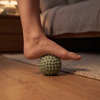Bare foot pressing down on the sage reset ball on a timber floor