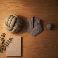 Overhead flat-lay of the Desk Reset Kit: knot pillow, heated wrap and reset ball on an oak desk