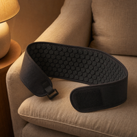 Charcoal acupressure belt laid open on a linen armchair in a warm lamplit living room