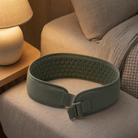 Sage acupressure belt laid open on a linen armchair in a warm lamplit living room