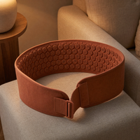 Terracotta acupressure belt laid open on a linen armchair in a warm lamplit living room