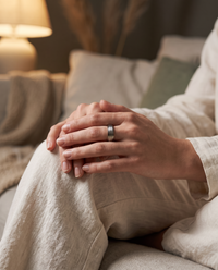 Hands resting in a lap, one thumb turning the outer band of the stainless steel reset ring