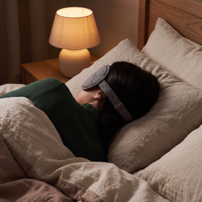 Woman asleep wearing the weighted sleep mask in a dark bedroom
