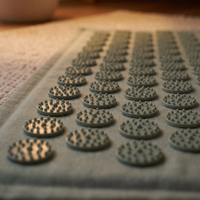 Close-up of the sage acupressure mat's blunt contact points in warm lamplight